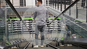 A man with a trolley on escalator in a hardware store, back view