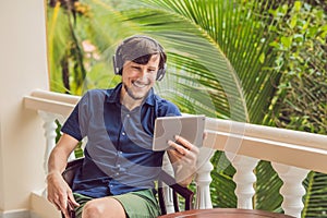 Man in tropics talking with friends and family on video call using a tablet and wireless headphones