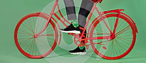 Man in trousers, bright socks and suede sneakers riding red bicycle