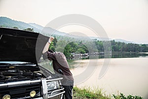 Man try to fix a car engine problem on a local road Chiang mai Thailand