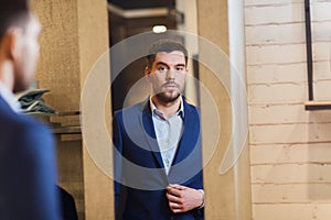 Man trying jacket on at mirror in clothing store