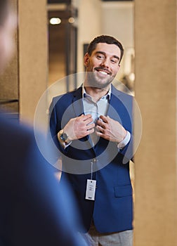 Man trying jacket on at mirror in clothing store