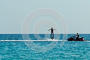 Man trying stand on flyboard. Water extreme sports