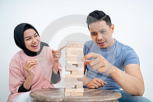 Man trying to pick up blocks when girlfriend laughs
