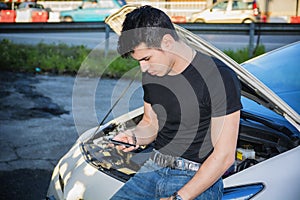 Man trying to repair car and seeking help on phone