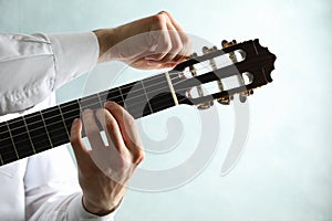 Man tunes classic guitar against light background