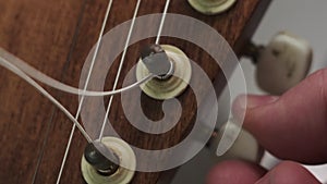 man is tuning musical instrument. The musician twists the guitar tuner pegs and pulls the strings to start playing music