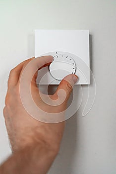 Man turning on heating thermostat