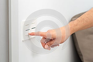 Man turning on the light switch at home