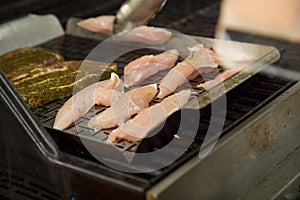 Man turning and roasting chicken filet and pork neck steaks on gas grill BBQ barbecue in stainless steel basket pan