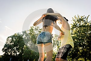 Mann turning woman dancing in the grass in summer park