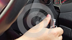 Man turns ignition key near steering wheel in car salon closeup
