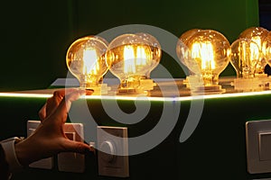 A man turns on round energy-efficient light bulbs in a glass bulb with warm light