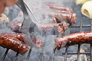 Man turns sausages on a smoking grill with a fork. Sausages BBQ smoking