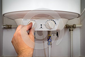 Man turns on the switch on control panel of home electric water heater boiler