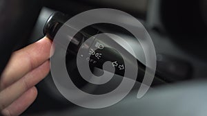 A man turns on the turn signal to the right on the lever in the car. Automotive panel close-up.