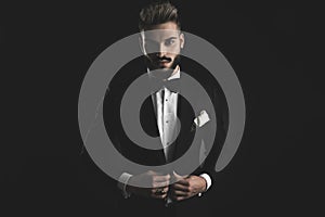Man in tuxedo adjusting his lounge jacket with both hands photo