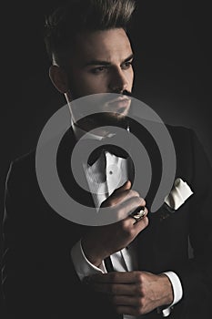 Man in tuxedo fixing his sleeve while looking away photo