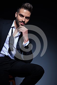 Man in tuxedo with untied bowtie is smiling and thinking