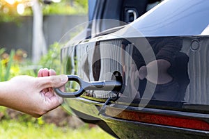 A man twists a towing eyelet into a passenger car to pull the car out of the mud, close-up