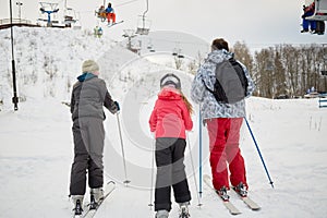 Man with two children ski to cableway in winter photo