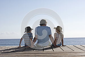 Man With Two Kids Sitting On Jetty