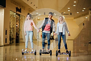 Man and two woman riding on Hoverboard in mall