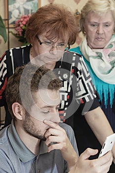 Man and two women look at the smartphone screen