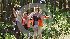 A man and two women are standing in a forest