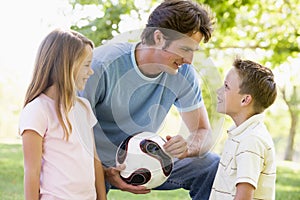 Man and two young children holding volleyball