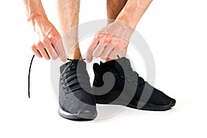 A man tying his shoelaces on black sports shoes. For sports. Iso