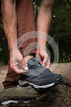 Man tying his trekking shoes on a branch