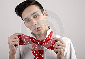Man tying a red scarf with dots around his neck.