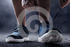 Man tying running shoes on asphalt background