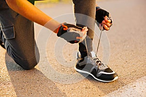 A man tying shoelaces on sneakers. A sportsman tying shoelaces on sneakers close up. A male athlete tying shoelaces on