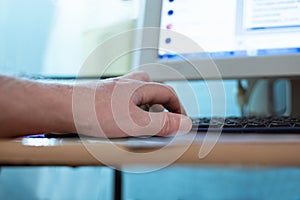 Man typing on computer keyboard with his left hand, remote work at home,