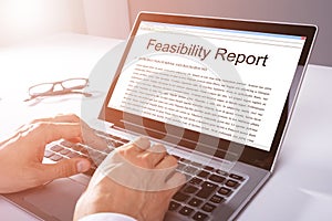 Man Typing Feasibility Report On Laptop