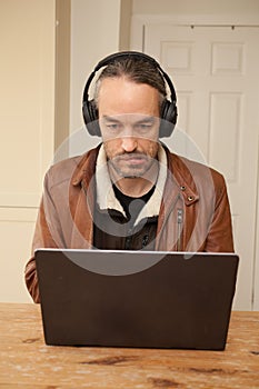 A man typing on his laptop whilst listening to music