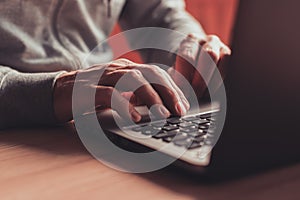 Man typing laptop computer keyboard in home office, closeup of hands