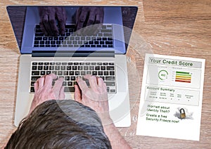 Man typing on laptop with credit report