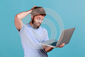 Man typing on laptop, having new idea and planning own strategy, holding one hand on the head.