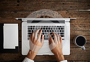 A man is typing on laptop keyboard on modern white office desk
