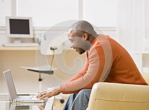 Man typing on laptop in livingroom