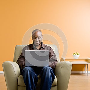 Man typing on laptop in livingroom