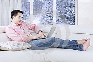 Man typing with laptop on sofa