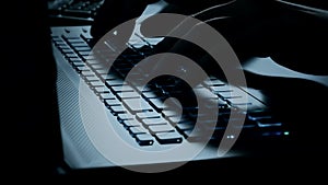 Man typing on notebook keyboard with blue light tint