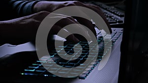 Man typing on notebook keyboard with blue light tint