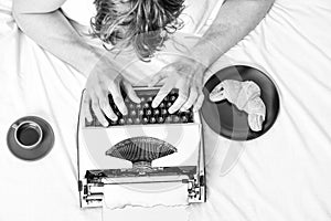 Man typing retro writing machine. Old typewriter on bedclothes. Male hands type story or report using vintage typewriter