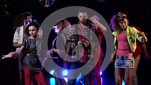 Man typing sms on the phone around dancing people the fun . Black background. Smoke background