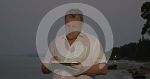 Man typing on tablet while standing on beach